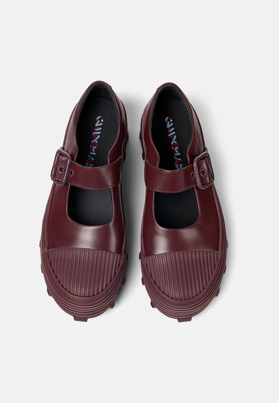 Maroon rubber shoes with a secure buckle, cutout vamp, and textured, ribbed toe. Features a patterned insole and chunky sole.