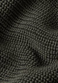 Tessuto grigio scuro lavorato a maglia con un motivo strutturato e creste in rilievo. Il filato è spesso e tessuto strettamente, creando profondità e interesse visivo.