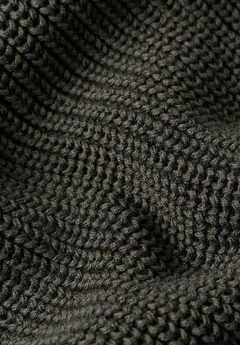 Tissu tricoté gris foncé avec un motif texturé à crêtes surélevées. Le fil est épais et tissé serré, créant de la profondeur et un intérêt visuel.