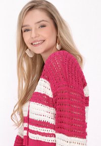 Rosa och vit randig stickad cardigan med öppet vävmönster, med v-ringning och långa ärmar. Mjuk textur med en avslappnad passform.
