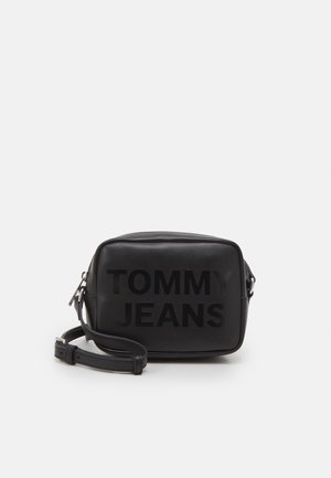 Schwarze Leder-Umhängetasche mit verstellbarem Riemen, vorne mit eingeprägtem "TOMMY JEANS"-Logo.