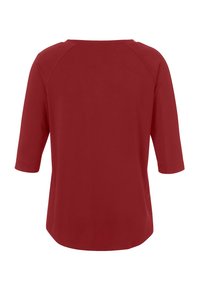 Haut rouge à manches trois-quarts en tissu doux avec un col rond et une coupe décontractée, présentant une texture lisse et un design simple.