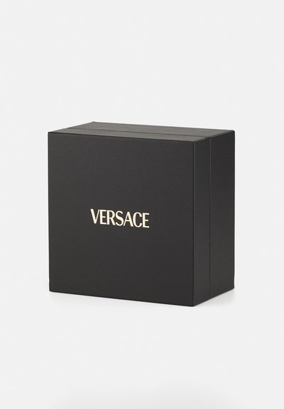 Mustatooniline must kast sileda tekstuuriga, mille esipinnal on kuldne "VERSACE" logo. Kastil on erksad servad ja minimalistlik disain.