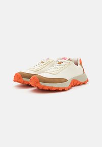 Sneakers casual con una toma superiore crema, dettagli in suede marrone e suola in gomma arancione. Presentano lacci e un'etichetta di marca sul tallone.