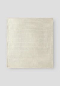 Cotton blanket in cream with a subtle grid pattern in pink and blue. Soft texture and lightweight design suitable for layering.
