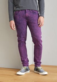 Lila denimjeans med en urtvättad textur, slim fit, framfickor och en grå långärmad skjorta; matchade med grå högskor.