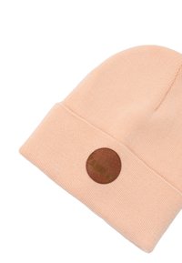 Brązowa, szydełkowa czapka w kolorze brzoskwiniowym z podwiniętym brzegiem, z okrągłą, skórzaną naszywką zdobioną wzorem.