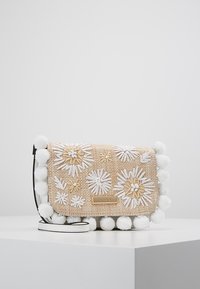 Borsa intrecciata color tan con ricamo floreale bianco, bordino in pom-pom morbido e una placca con logo dorato. Presenta una tracolla removibile.