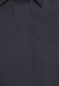 Marinblå skjorttyg med en slät textur, med en klassisk krage och en vertikal sömdetalj på framsidan.