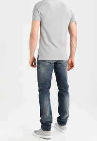 Grå t-shirt med korta ärmar, denimjeans och grå sneakers. Jeansen är blekta med regular fit, och t-shirten har sidofickor.