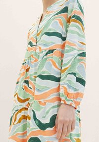 Langarmkleid mit V-Ausschnitt, das ein gewelltes Muster in Grün, Orange und Blau aufweist, aus leichtem, strukturiertem Stoff gefertigt.