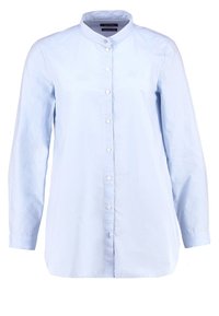 Chemise bleu clair à manches longues avec col officier et fermeture boutonnée devant sur fond blanc.