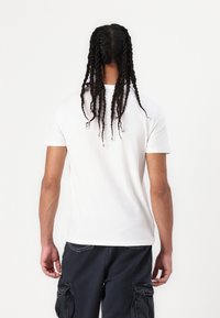 Witte katoen T-shirt met korte mouwen, ronde hals en een losse pasvorm. De stof is glad, zonder zichtbare patronen of accenten.