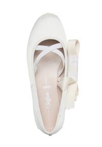 Ballerine blanche avec des bandes élastiques croisées et un ruban nœud détachable assorti placé à côté, vue de dessus.