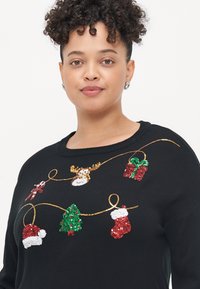 Pulover negru cu embellismente din paiete reprezentând motive de Crăciun: un brad, cadouri, ciorapi și un ren, toate pe un detaliu din fir auriu.