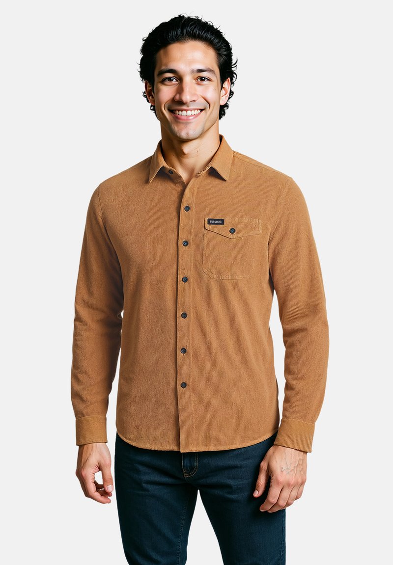 Bruine corduroy overhemd met knoopsluiting aan de voorkant, lange mouwen en een borstzak. Voorzien van zwarte knopen en een logo patch op de zak.