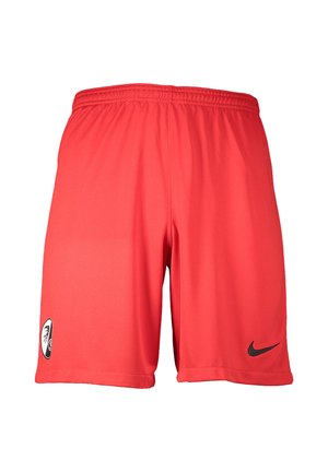 Rote Sportshorts mit elastischem Bund, mit schwarzem Nike-Logo am rechten Bein und einem schwarz-weißen Wappen am linken Bein.
