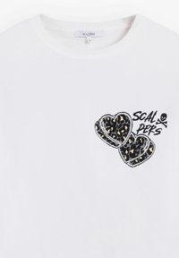 Camiseta de manga corta blanca con diseños de corazón de estampado de leopardo y el texto negro "SCALPERS". Material de algodón suave con un escote en forma de barco.