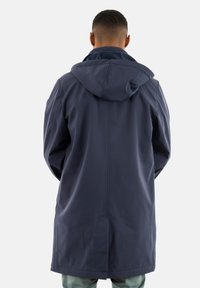 Abrigo impermeable azul marino con capucha, textura en la superficie, diseño largo y corte holgado. Cuenta con una abertura en la espalda y sutiles detalles en las costuras.