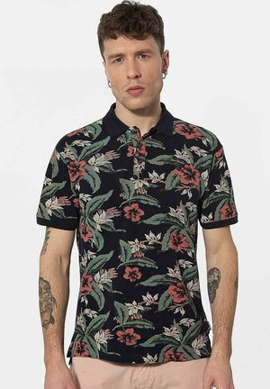 Polo à manches courtes en bleu marine avec un motif floral comportant des fleurs roses et blanches, des feuilles vertes et un col noir. Tissu en mélange de coton.