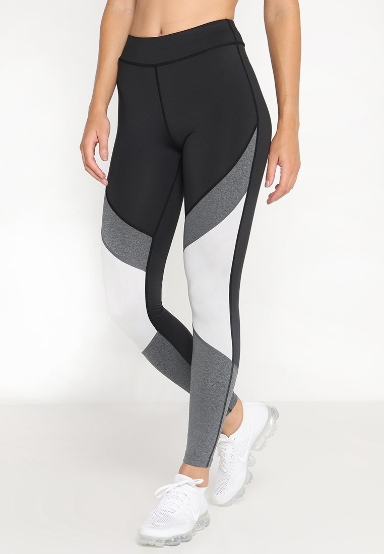 Leggings atletici a vita alta con una combinazione di pannelli neri, bianchi e grigi. Realizzati in un tessuto elastico e traspirante con una texture liscia.