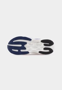 Σόλα αθλητικού παπουτσιού με μπλε, μαύρα και λευκά υφάσματα από καουτσούκ σε λευκό φόντο.