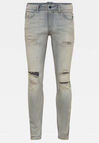 Jeans ajustados en denim azul claro deslavado, con detalles desgastados y roturas en las rodillas, diseño clásico de cinco bolsillos y cierre de botón azul.