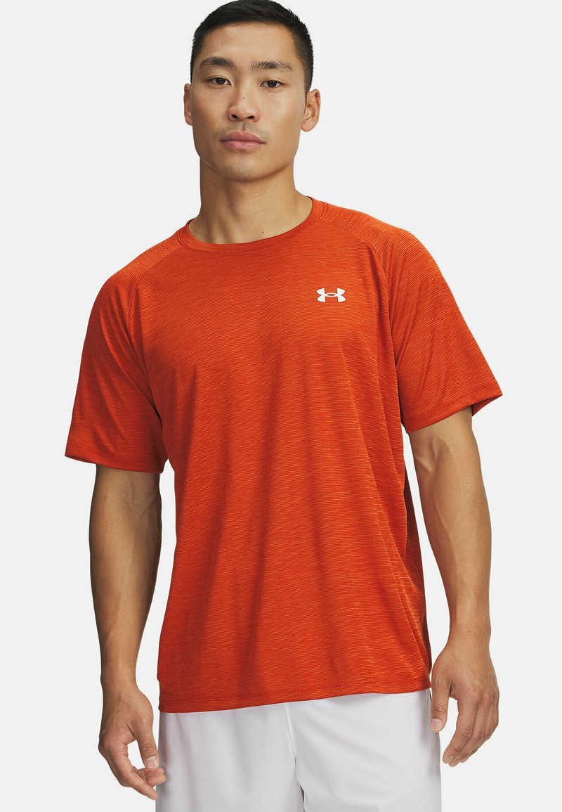 Camiseta atlética de manga corta en un brillante color naranja, hecha de una tela texturizada; presenta un logo blanco en el pecho.