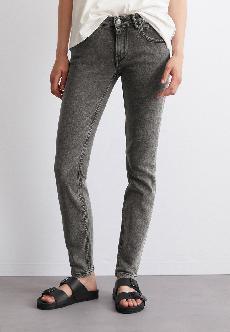Šedé džíny z denimu se slim fit, pěti kapsami, zapínáním na knoflík a jemným vyblednutím, doplněné černými plochými sandály.