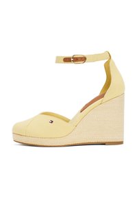 Gele canvas wedge-schoen met open teen, enkelbandje en tan leren sluiting; heeft een gestructureerde geweven tussenzool en een klein logo detail.