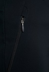 Tissu noir avec une fermeture éclair verticale partiellement fermée avec une tirette en caoutchouc noir.