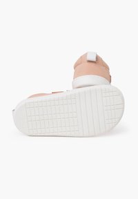 Scarpa in suede rosa chiaro con suola in gomma bianca e battistrada testurizzato; presenta una fascia bianca e un'etichetta posteriore per indossarla facilmente.