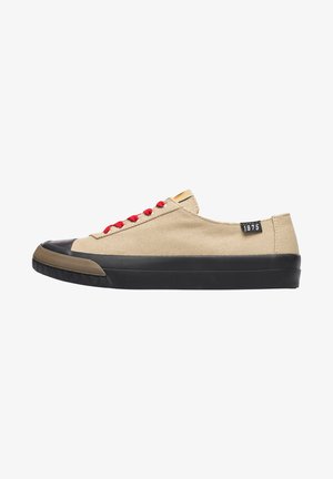 Zapatillas de lona beige con cordones rojos, puntera de goma negra y un upper texturizado. Presenta una suela negra y una etiqueta de logo en el lateral.