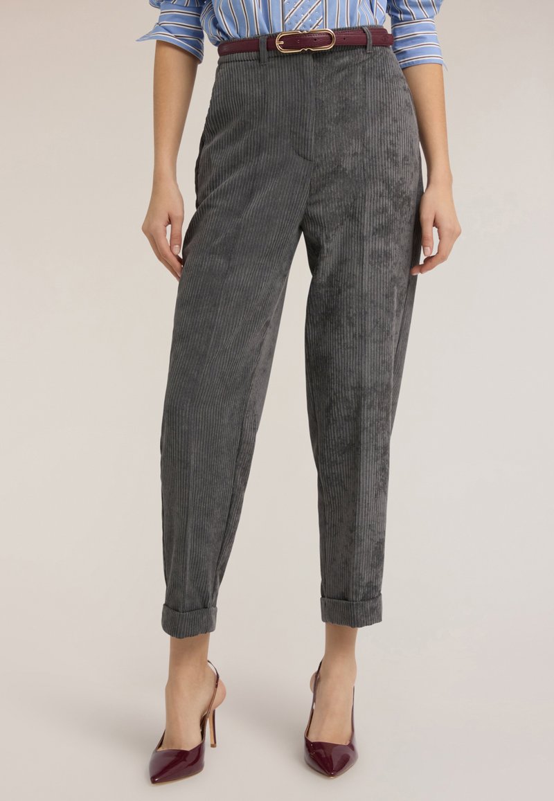 Graue Cordhosen mit hoher Taille, seitlichen Taschen, aufgekrempelten Bündchen und einem bordeauxfarbenen Gürtel, kombiniert mit bordeauxfarbenen spitzen Absatzschuhen.