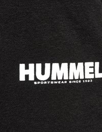 Tela negra con texto en blanco y negrita "HUMMEL" y debajo impreso texto más pequeño "SPORTSWEAR SINCE 1923".