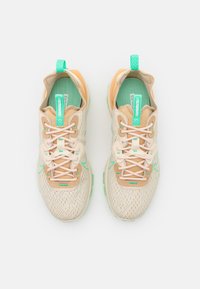 Beiga sportskor med teal-accenter och mönstrad meshovandel. Har ett framträdande snörningssystem och vadderad tunga för komfort.