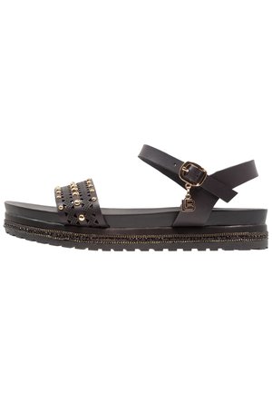 Sort flad sandal med nittet og perforeret frontrem, ankelspænde med guldsmykke og dekorativ perlebesat sålkant.