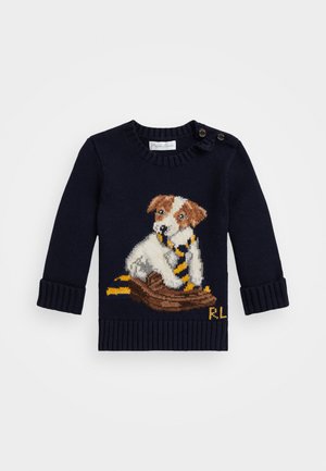 Suéter de punto azul marino con un diseño tejido de un perro sobre un tronco, con acentos a rayas amarillas y negras y detalle de botón en el hombro.