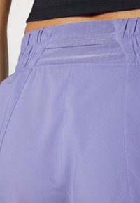 Purple athletic shorts with an elastic waistband and pleated design. The fabric appears smooth with a slight sheen and no visible patterns.
