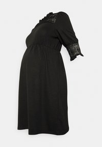 Vestido de maternidade preto com mangas curtas, decote franzido e pormenores em renda. Design fluído concebido para a silhueta de uma mulher grávida.