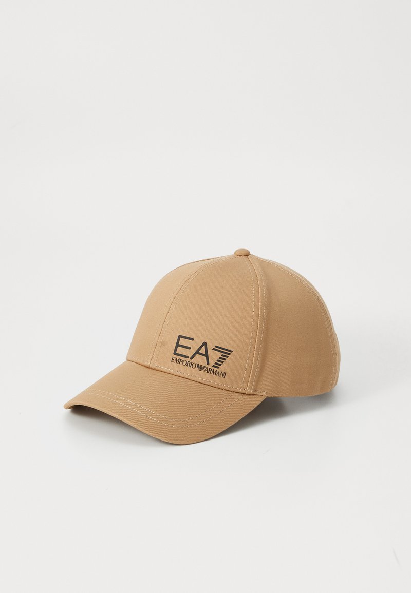 Beige baseball cap with a curved brim, featuring a black EA7 logo on the front. Made of smooth fabric with visible stitching details.