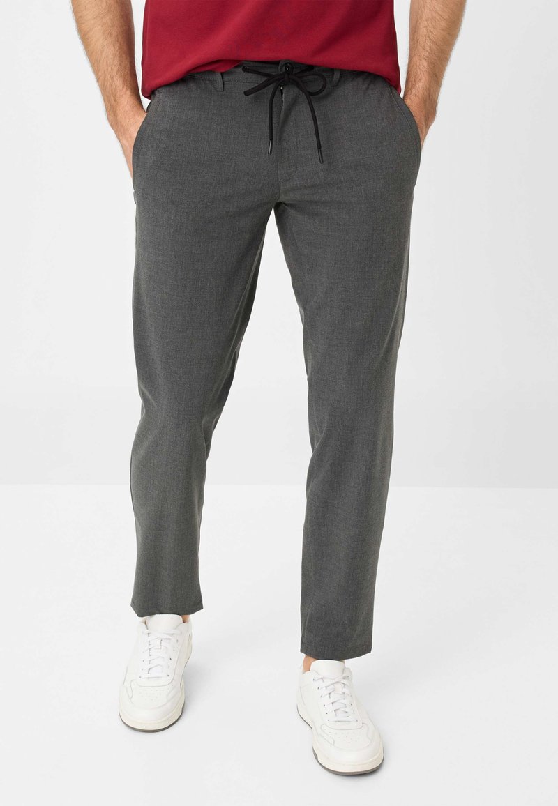 Pantalons gris fuselés en tissu texturé, dotés d'une taille à cordon de serrage et de poches latérales ; associés à des baskets blanches.