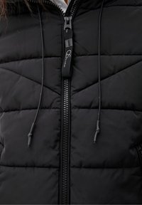 Czarna kamizelka puchowa z zamkiem błyskawicznym, pionowym wzorem pikowania i regulowanymi sznurkami. Materiał wydaje się być gładki i izolowany.