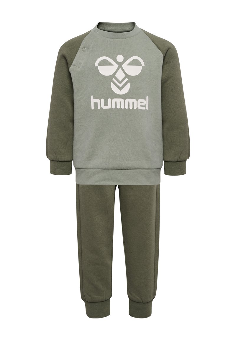 Olivgrüner Pullover mit wei�ßem "hummel"-Logo und Raglanärmeln. Passende olivgrüne Hose mit elastischen Bündchen und glatter Textur.