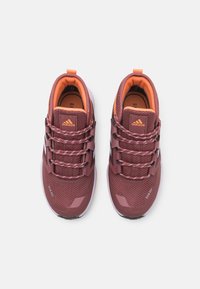 Burgundowe buty sportowe z teksturowaną cholewką, jasnopomarańczowymi akcentami, elastycznymi sznurowadłami oraz amortyzowaną podeszwą, zaprojektowane z myślą o komforcie i wsparciu.