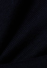 Marineblauer Strickstoff mit einer weichen Textur. Verfügt über ein geripptes Design und glatte Abschnitte, die eine tiefe, einheitliche Farbe zeigen.