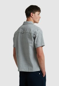 Korte mouwen shirt in een blauw-wit ruitpatroon. Gemaakt van een gestructureerde stof met een ontspannen pasvorm en een inzetstuk op de rug.