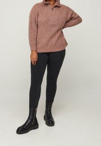 Maglione rosa con colletto a mezza zip, lavorazione a maglia tessurizzata, abbinato a jeans skinny neri e stivali ankle neri con plateau.