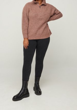 Maglione rosa con colletto a mezza zip, lavorazione a maglia tessurizzata, abbinato a jeans skinny neri e stivali ankle neri con plateau.