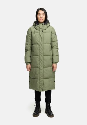 Grøn polstret lang frakke med høj krave og hætte, der har trykknapper, en quiltet design og sidelommer. Båret over mørke bukser og støvler.